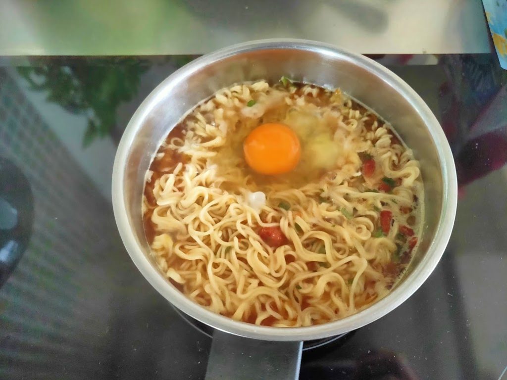花雕鶏麺調理中、卵を投入